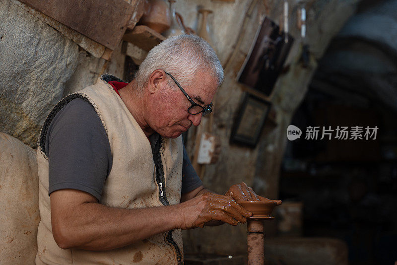 一位老人正在制作一个陶杯