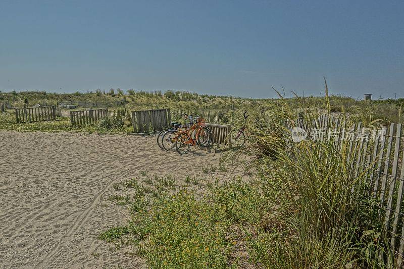 沙滩上的篱笆旁停着几辆自行车和一辆手推车