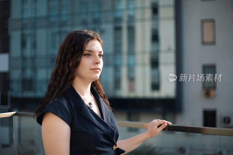 一个穿裙子的女人站在一栋办公楼附近，把目光移开