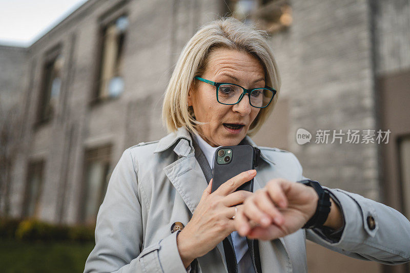 一名女子成熟女站在城市户外使用智能手表