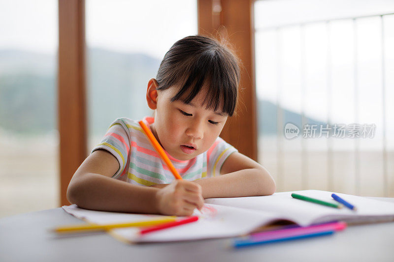 一个小女孩正在家里用铅笔给一本涂色书涂色