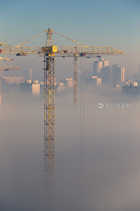 工地上的起重机。雾蒙蒙的城市景象。清晨浓雾笼罩着一个居民区。