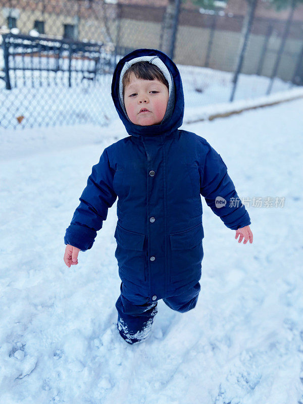 一个男孩站在公园的雪地里