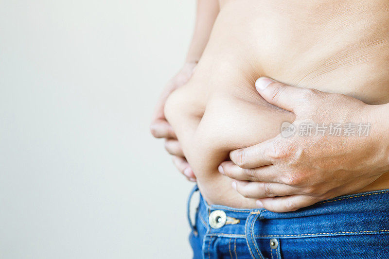 肥胖成熟男人检查身体超重腹部他的腹部为白色或肥胖背景。减肥概念。