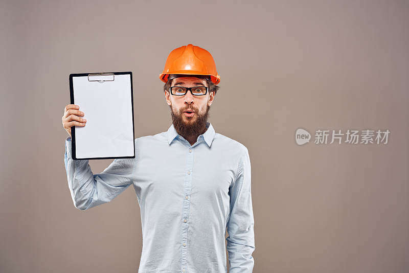 工业文件上戴着橙色安全帽的情绪化男子