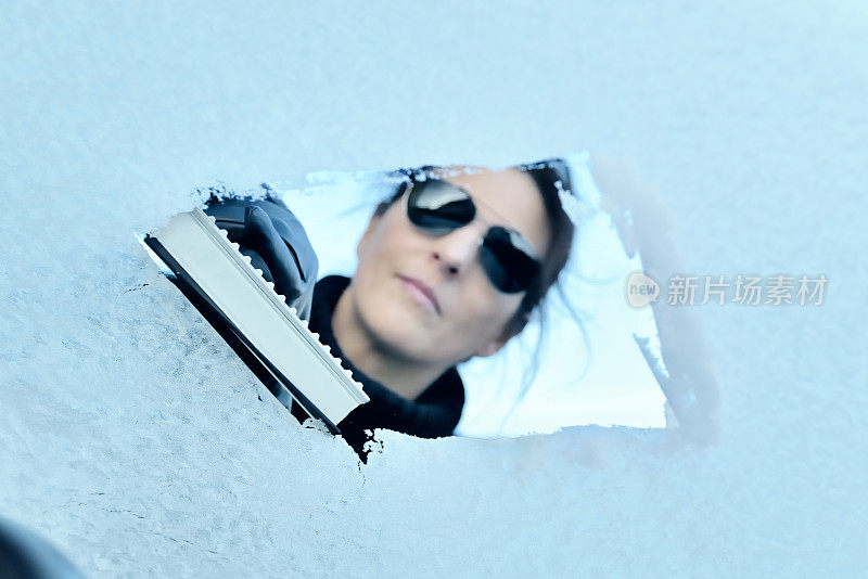 冬天开车-女人从挡风玻璃上刮冰
