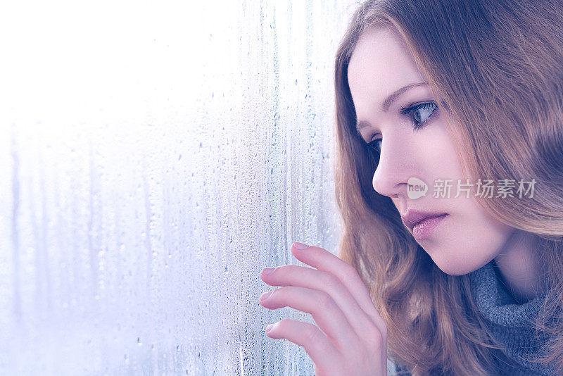 忧伤的女孩在雨中的窗口