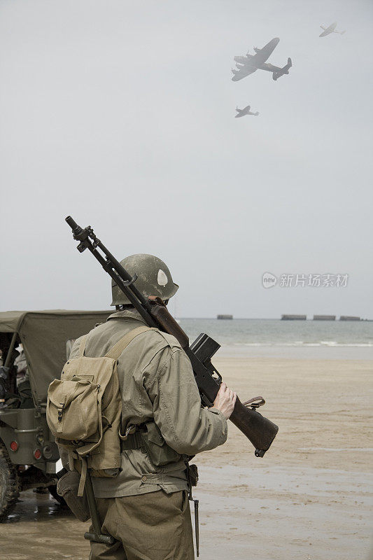 士兵看着飞机飞过诺曼底海滩