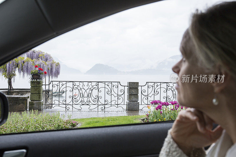 女人在车里放松，看着对面的湖，鲜花