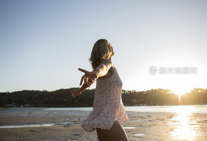 沙滩上的女孩在夕阳下跳舞