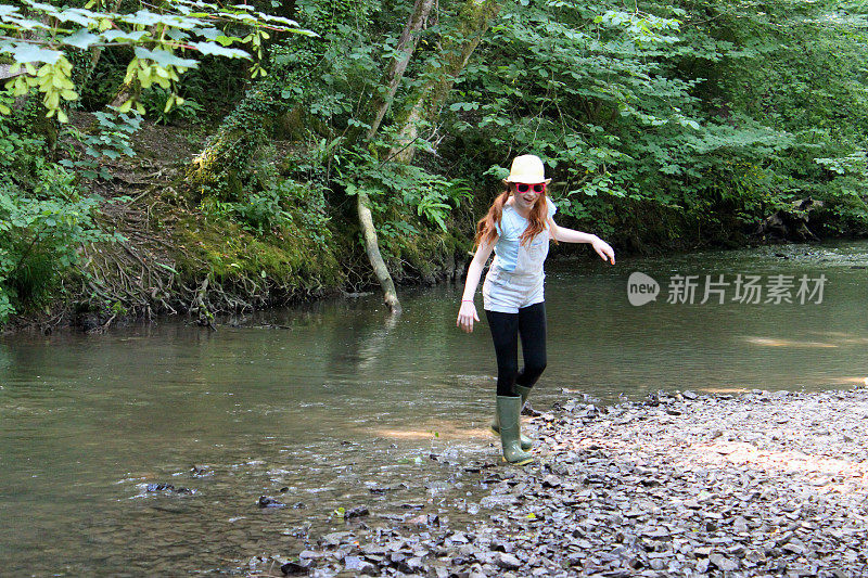 女孩的形象玩耍，划水，溅水，涉水在河流，林地