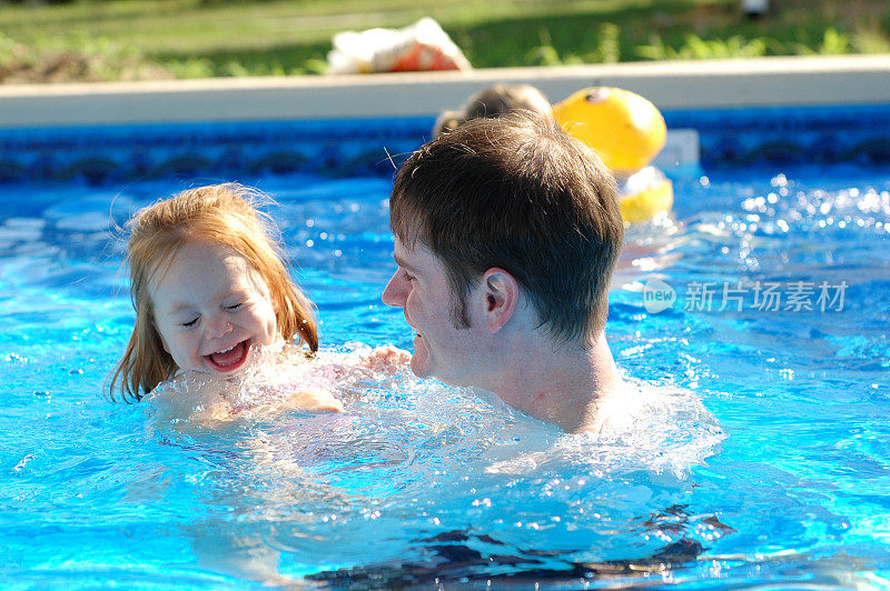 小女孩和爸爸在游泳池里戏水嬉笑