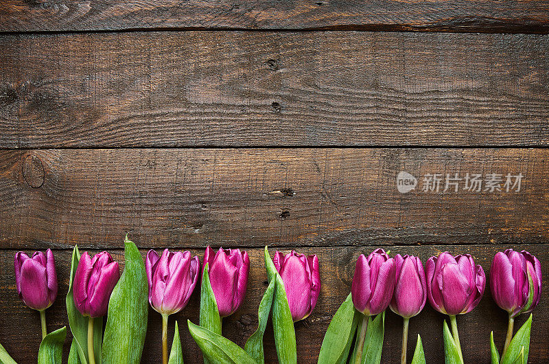 粉红色，郁金香束在深色的谷仓木板背景