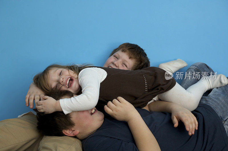 兄弟姐妹:可爱的超重儿童在蓝色的墙前嬉闹