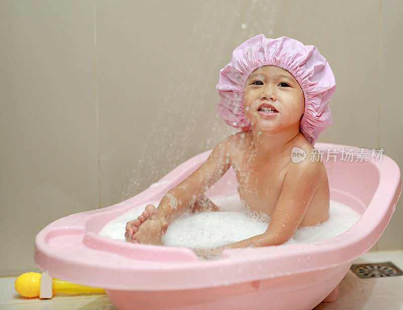 快乐的小男孩在一顶泡沫浴的帽子里。