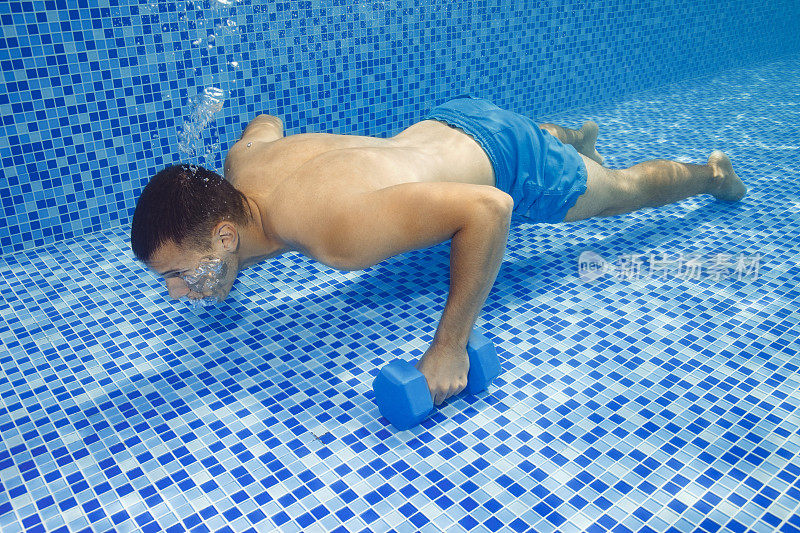 水下年轻人在游泳池里用哑铃训练