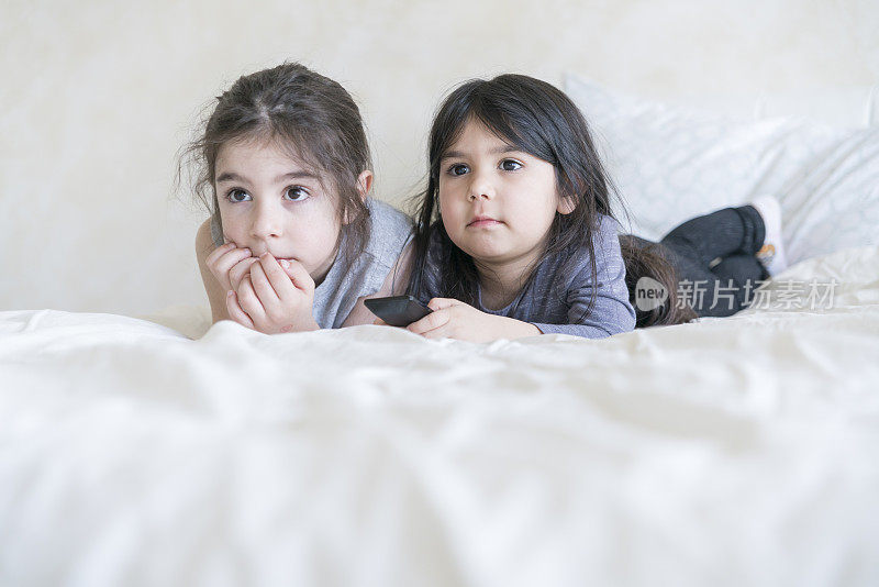 小女孩和小男孩在父母的床上看电视