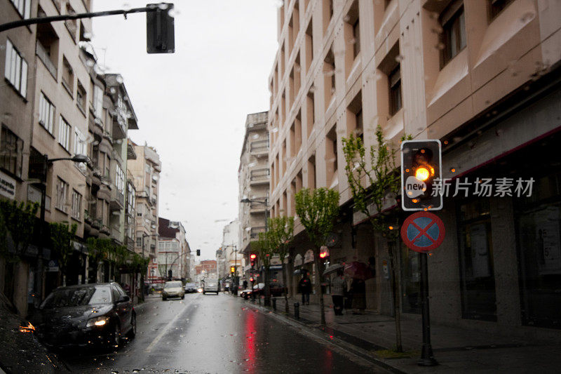 下雨天直线城市街景，琥珀色交通灯。