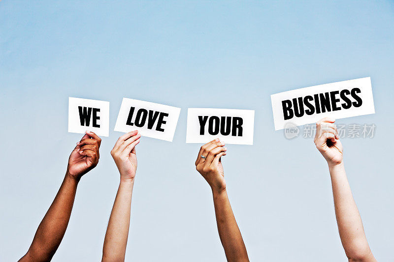 手持式标牌上写着“我们爱您的生意”，颜色是蓝色