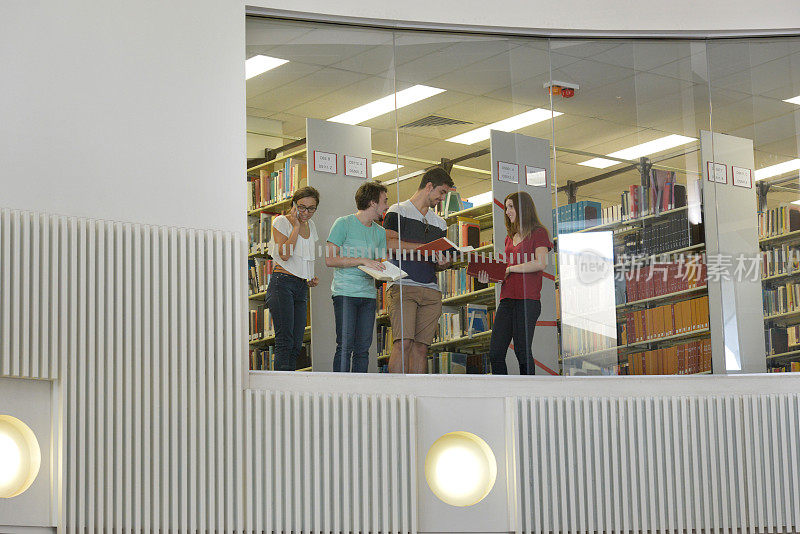 四个年轻人站在图书馆里看书