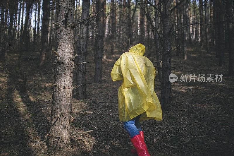 穿着雨衣的秋女在森林里行走