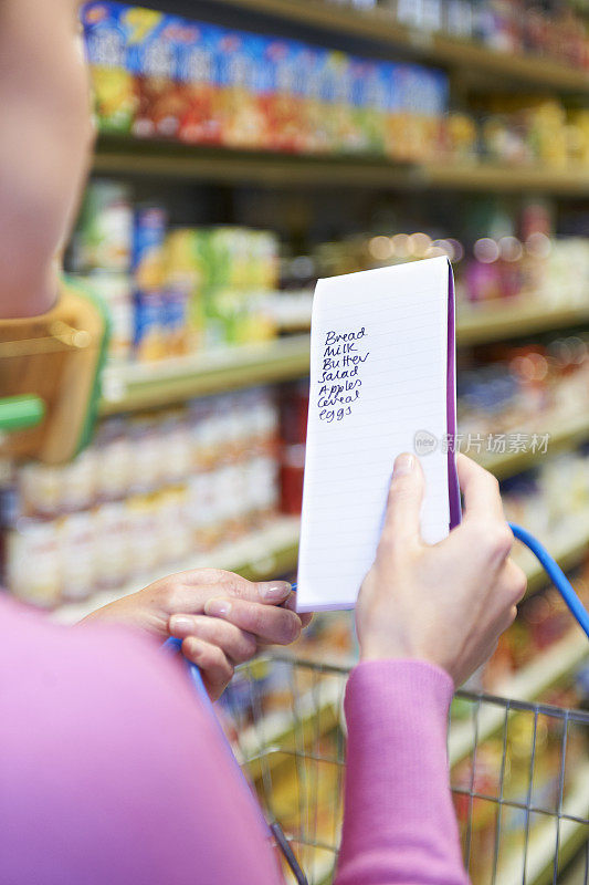 在超市里看购物清单的女人