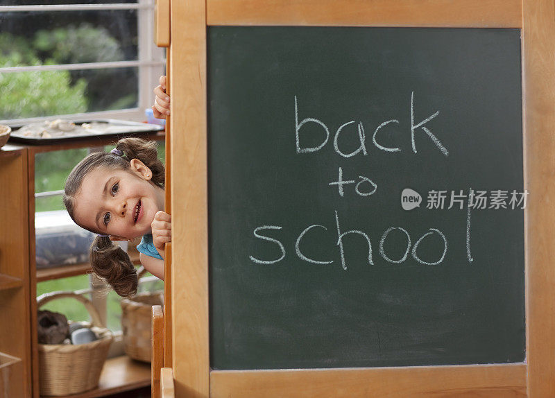 学前班的小女孩拿着黑板回到学校