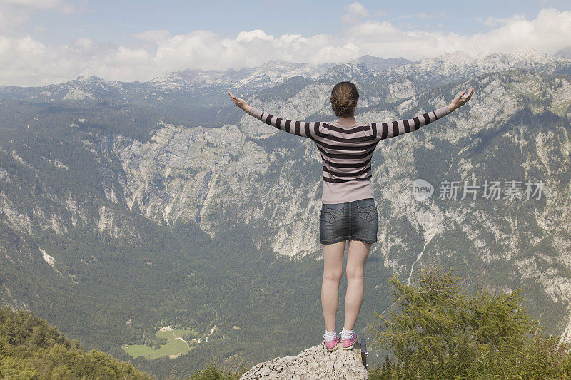 女人的双手伸向群山之上的天空