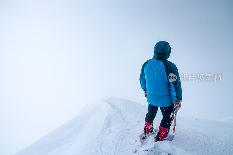 一个人站在冰川山峰上望着云