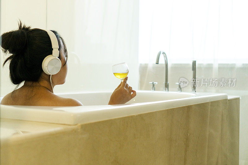 在浴缸里喝香槟听音乐的女孩