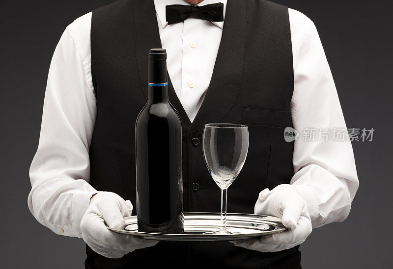 一个侍者端着一个小盘子、一个玻璃杯和一个酒瓶