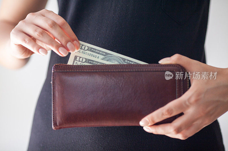 一个女人正在从钱包里取出钱