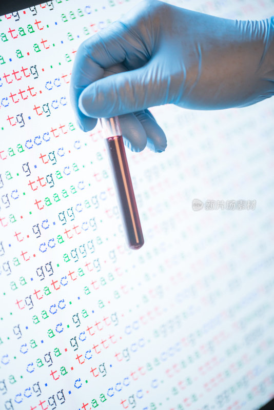 戴着手套的研究人员拿着屏幕上有颜色编码DNA序列的血样