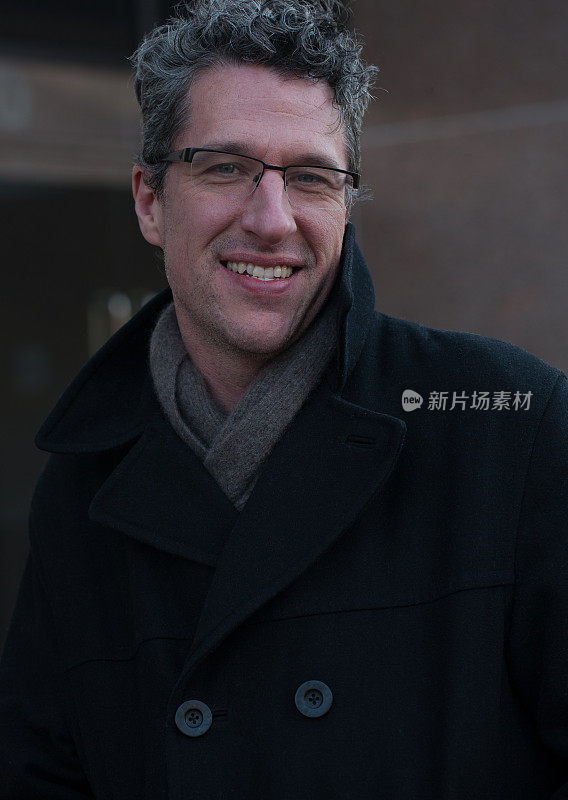 一个微笑的成熟的职业男子的肖像在冬季大衣