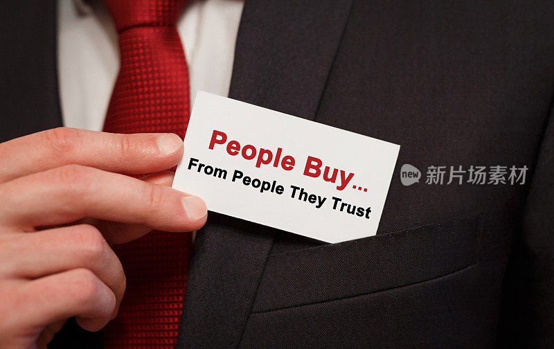 商人把一张写着“人们从他们信任的人那里买东西”的卡片放在口袋里