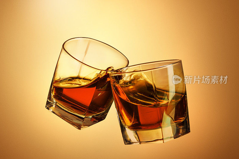 两杯威士忌在棕色杯中碰撞