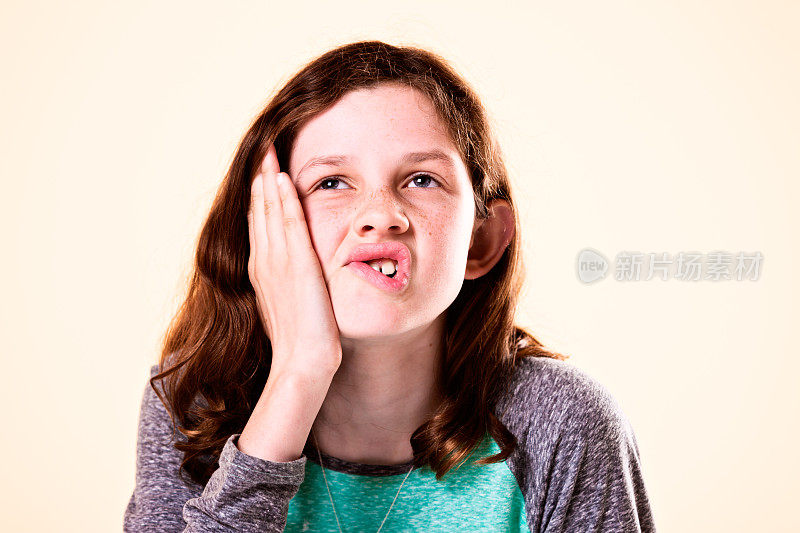 十来岁的女孩嚼嘴唇，思考，沮丧，或无聊