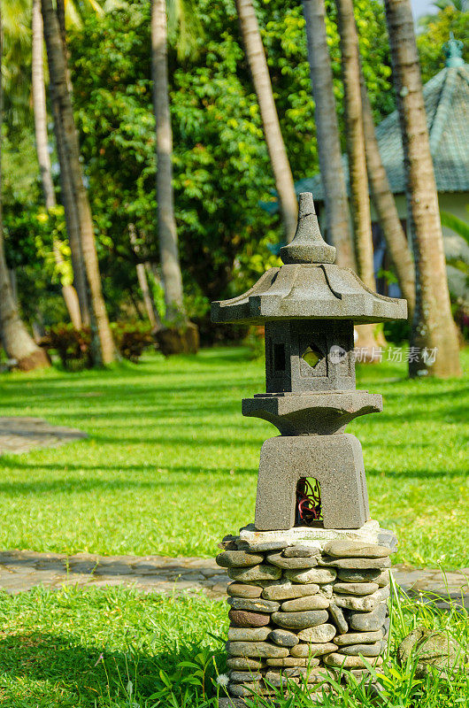 巴厘岛-小宝塔和棕榈树与绿色草地在日出放松