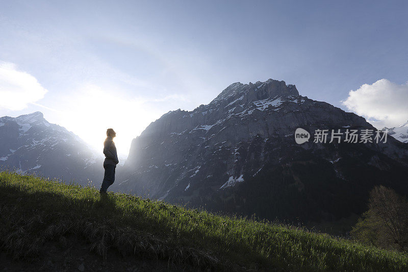 人走进草甸，在高耸的山脚下