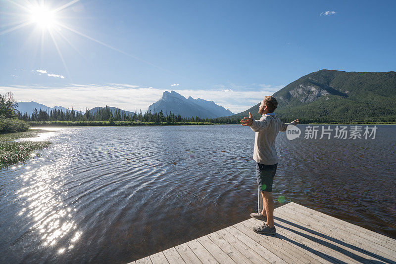 男人们在湖边的码头上张开双臂