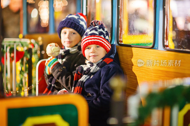 两个小男孩在圣诞市场的旋转木马上
