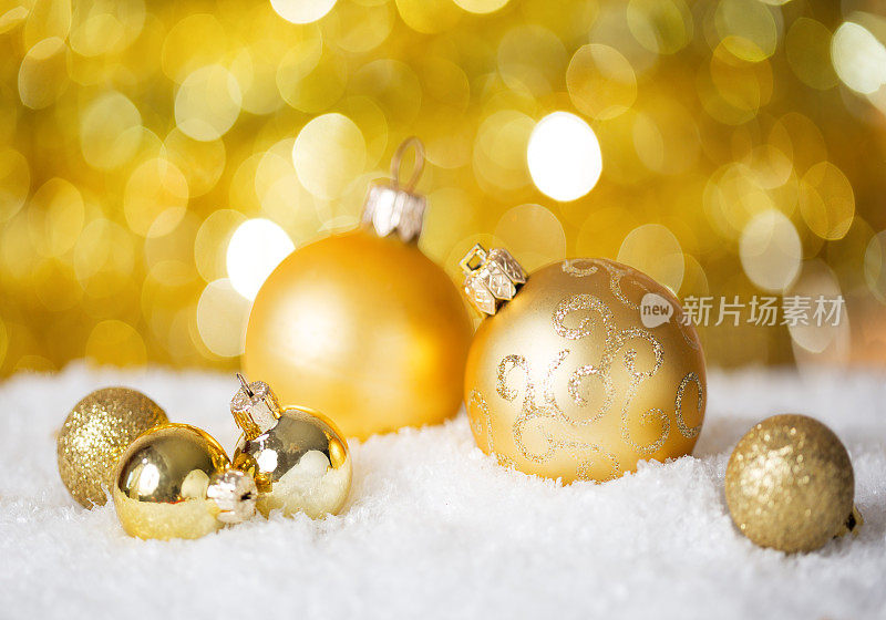金色的圣诞球在闪亮的背景上。非常浅的景深。有选择性的重点