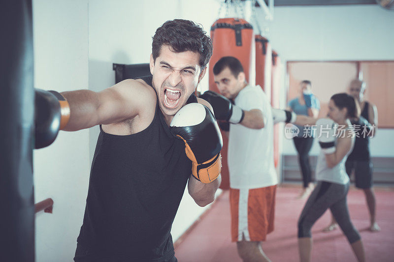 一个肌肉发达的男人正在打一个拳击袋