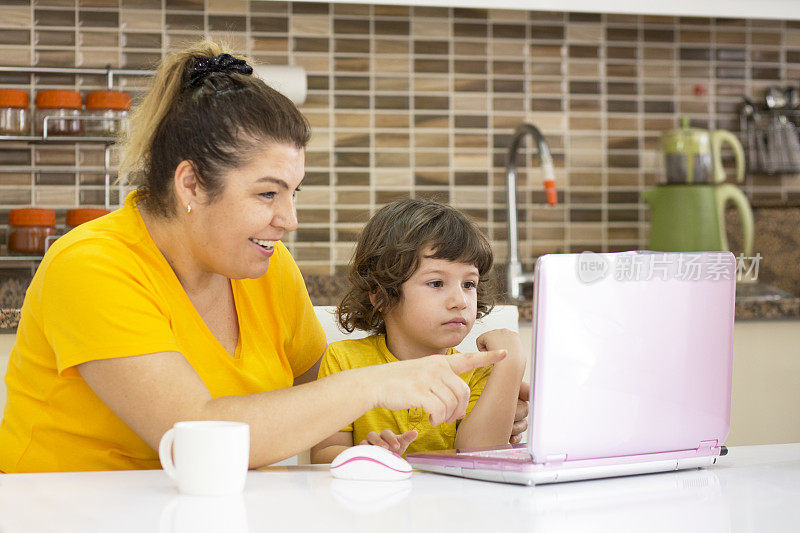 爱玩的妈妈和她的儿子在厨房使用数字平板电脑
