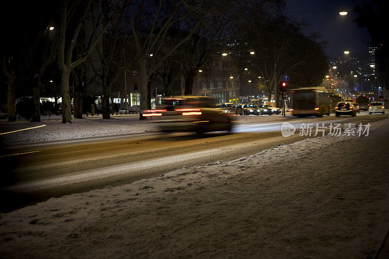 夜晚的街道上，积雪覆盖，车水马龙