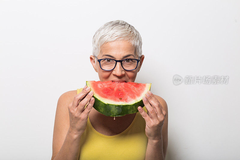 老女人戴着眼镜，咬着西瓜片