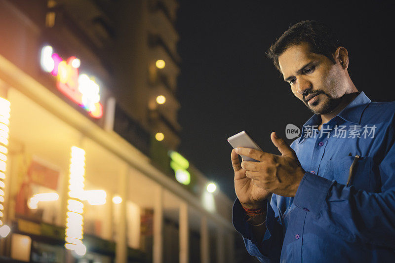 晚上在户外使用智能手机的中年商人。