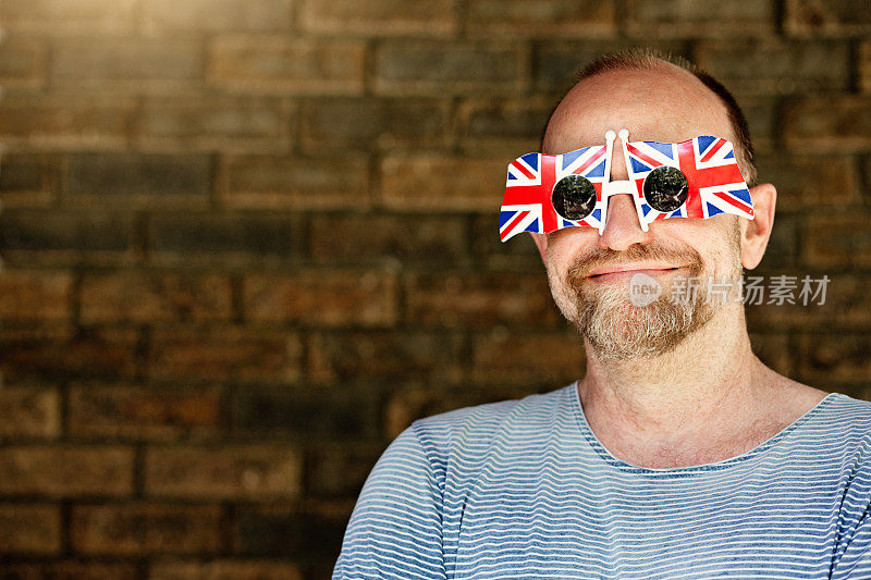 戴着英国国旗太阳镜的成熟英国男人对英国脱欧微笑着