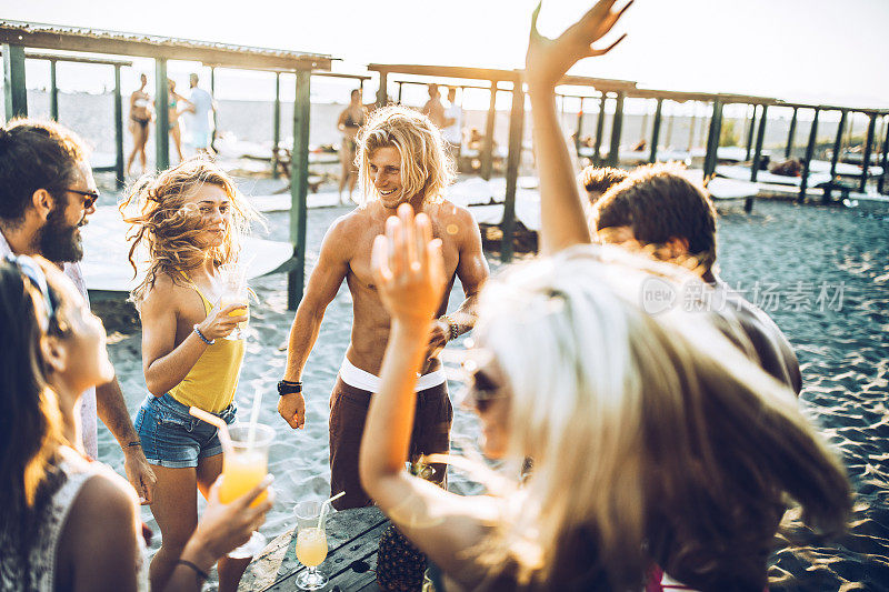 夏日里，一大群快乐的人在海滩聚会上跳舞。