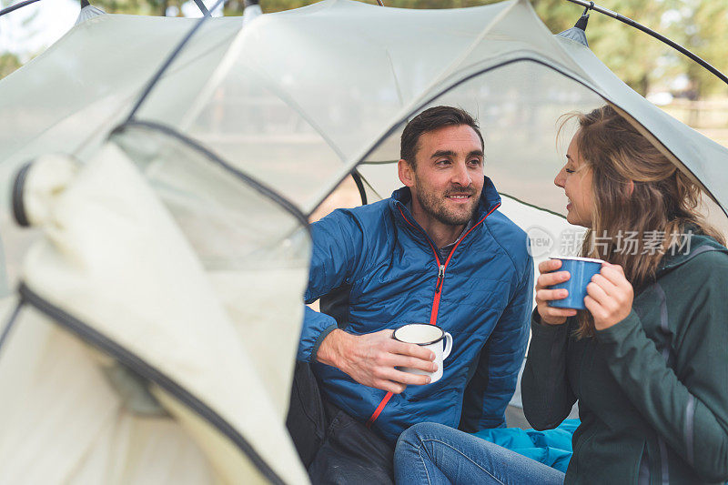 一对千禧年的夫妇在露营旅行中在帐篷里喝咖啡